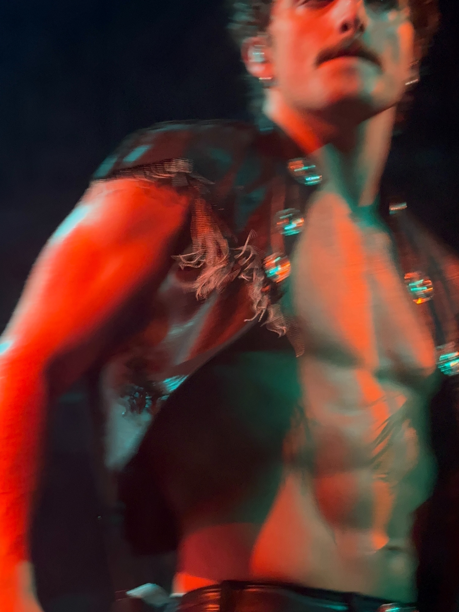 Motion-blurred concert photograph of a singer under red and teal lighting